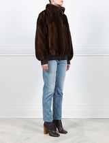SIDE VIEW-MAHOGANY MINK BOMBER JACKET-STAND COLLAR-FULL LENGTH SLEEVES-SLIT POCKETS-FRONT ZIP CLOSURE-GATHERED LEATHER TRIM AT WRISTS AND WAIST -25 INCH CENTER BACK LENGTH-BY POLOGEORGIS