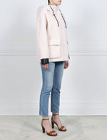 SIDE VIEW-IVORY HOODED BOMBER JACKET WITH BLACK LEATHER TRIM-DRAWSTRING HOOD  WITH METAL STOPPERS-FULL LENGTH SLEEVES WITH BLACK LEATHER CUFFS-BLACK LEATHER TRIMMED FLAP POCKETS-HIDDEN ZIP CLOSURE-28 INCH CENTER BACK LENGTH-BY POLOGEORGIS